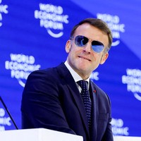 Di WEF yang berlangsung di Davos, Swiss, pada  Rabu (21/1/2026), Macron berpakaian rapi dalam balutan setelan, lengkap dengan dasi. Namun kontras dari gaya formalnya, sebuah kacamata aviator berlensa cermin yang menutupi matanya. (Foto: REUTERS/Denis Balibouse)