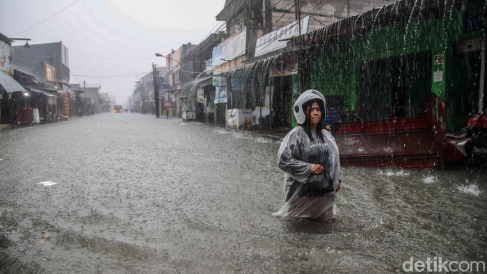 Sejumlah anak-anak sekolah bersama warga terpaksa menerobos genangan banjir saat hujan deras masih mengguyur kawasan Marakash, Pondok Ungu Permai, Kabupaten Bekasi, Jawa Barat, Kamis (22/1/2026). Hujan dengan intensitas tinggi yang turun sejak pagi membuat debit air terus meningkat dan merendam jalan utama permukiman tersebut. Ketinggian air dilaporkan mencapai sekitar 90 sentimeter atau hampir setinggi pinggang anak-anak, sehingga aktivitas warga menjadi sangat terganggu.