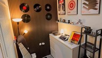 Ia memasang lantai stone plastic composite (SPC) bermoti kayu, wall panel berwarna hitam, serta mengecat ruangan warna putih. Ruangan ini diisi lemari pakaian, rak besi, cermin, rak besi, poster, vinil, dan lampu berdiri. Foto: Dok. Ahmad Pawetyo Putro
