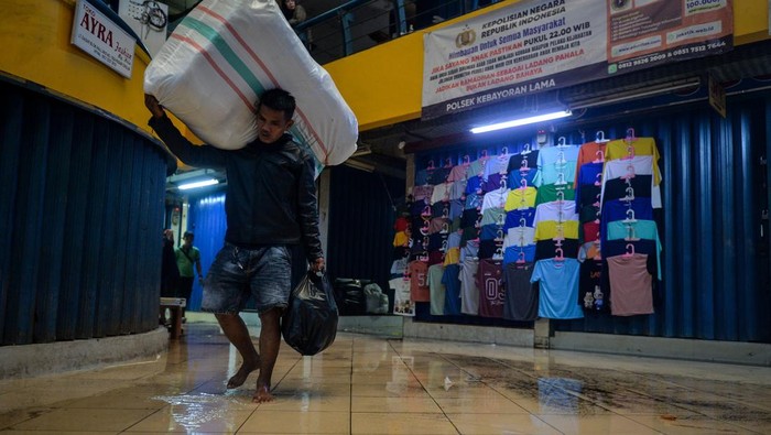 Buruh angkut melihat kondisi genangan air di Pasar Cipulir, Jakarta, Kamis (22/1/2026). Menurut pedagang, genangan air sering terjadi ketika hujan deras yang diduga akibat saluran drainase di luar area pasar tersumbat sehingga luapan air masuk ke dalam pusat grosir tersebut dan menghambat kegiatan perdagangan. ANTARA FOTO/Putra M. Akbar/agr