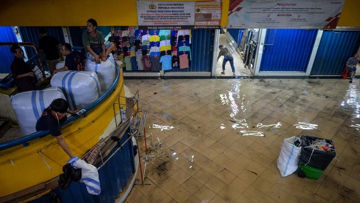 Buruh angkut melihat kondisi genangan air di Pasar Cipulir, Jakarta, Kamis (22/1/2026). Menurut pedagang, genangan air sering terjadi ketika hujan deras yang diduga akibat saluran drainase di luar area pasar tersumbat sehingga luapan air masuk ke dalam pusat grosir tersebut dan menghambat kegiatan perdagangan. ANTARA FOTO/Putra M. Akbar/agr