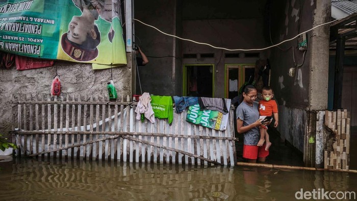 Warga beraktivitas di tengah banjir yang merendam Perumahan Subsidi Mutiara Indah, Tambun Utara, Kabupaten Bekasi, Jawa Barat, Jumat (23/1/2026).