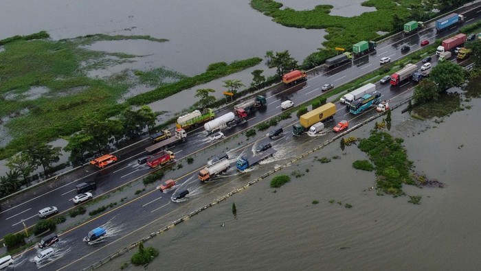 Foto udara sejumlah kendaraan menerobos banjir di ruas tol Tangerang-Merak KM 50 di Cikande, Kabupaten Serang, Banten, Jumat (23/1/2026). Banjir setinggi kurang lebih 40 sentimeter yang merendam lajur satu dan dua akibat luapan Sungai Ciujung serta curah hujan tinggi tersebut menyebabkan arus lalu lintas dari arah Jakarta menuju Merak tersendat dan hanya dapat dilalui kendaraan melalui lajur tiga (lajur cepat). ANTARA FOTO/Muhammad Bagus Khoirunas/bar