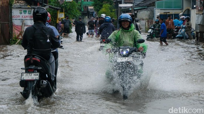 Pesepeda motor menerjang banjir di Komplek Ciledug Indah, Tangerang, Jumat (23/1/2026). Banjir terjadi akibat luapan Kali Angke.