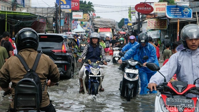 Pengendara mendorong motornya yang mati akibat terendam banjir di jalan KH Hasyim Ashari, Tangerang, Banten, Jumat (23/1/2026). Banjir membuat lalu-lintas menjadi semrawut.