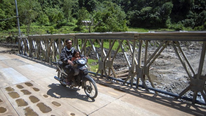 Warga melintasi jembatan bailey di Jorong Aia Taganang, Matur, Agam, Sumatera Barat, Minggu (25/1/2026). TNI-AD menyelesaikan pembangunan satu unit jembatan bailey yang menghubungkan Kecamatan Matur dan Palupuh, Agam, karena jembatan permanen hancur akibat banjir bandang pada November 2025. ANTARA FOTO/Iggoy el Fitra