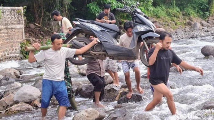 Warga terpaksa menyeberangi sungai akibat banjir Situbondo.