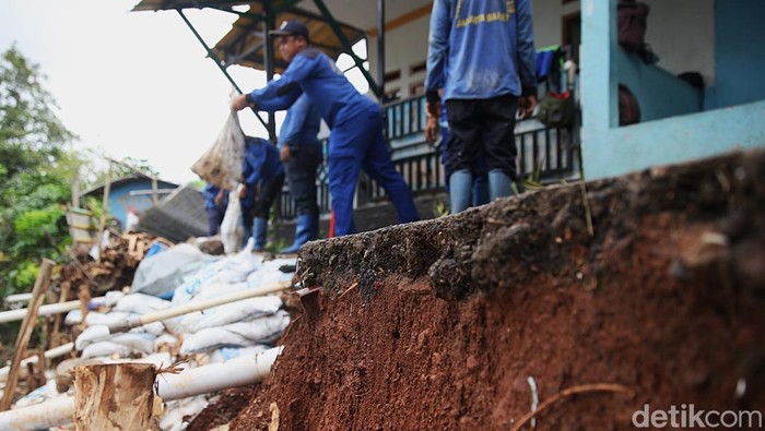 Petugas Dinas Sumber Daya Air (SDA) memindahkan batu kali untuk pembangunan turap bronjong di bantaran Kali Angke, Kembangan Selatan, Jakarta Barat, Senin (26/1/2026).