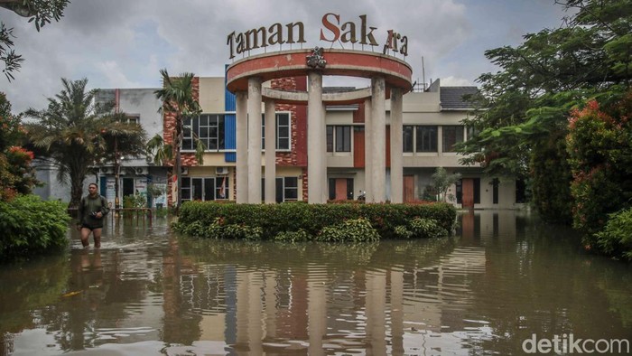 Sejumlah warga tetap beraktivitas di tengah banjir yang merendam kawasan perumahan cluster Taman Sakura, Babelan, Kabupaten Bekasi, Jawa Barat, Senin (26/1/2026).