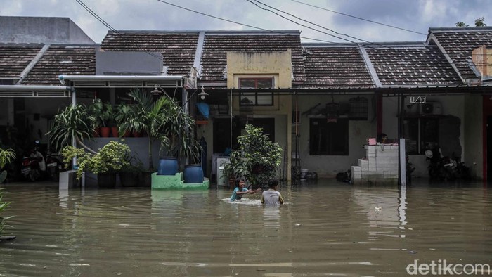 Sejumlah warga tetap beraktivitas di tengah banjir yang merendam kawasan perumahan cluster Taman Sakura, Babelan, Kabupaten Bekasi, Jawa Barat, Senin (26/1/2026).