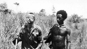 Seorang penduduk asli Papua Nugini membantu tentara Australia yang terluka pada tahun 1942. Mereka berperan penting dalam membimbing dan menyelamatkan nyawa banyak prajurit Australia. Foto: Boredpnada