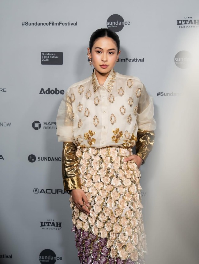 Aktris 31 tahun itu berbalut outfit dengan permainan layering yang sophisticated dari koleksi Biyan Spring-Summer 2026. Tampak baju lengan panjang emas dilapisi kemeja oversized yang berhiaska detail embelishment keemasan sehingga memberi sentuhan glamor. Rok high-waist hadir dengan tampilan dramatis lewat aplikasi sequin berbentuk bunga tiga dimensi nan memukau. (Foto: Instagram/@maudyayunda)
