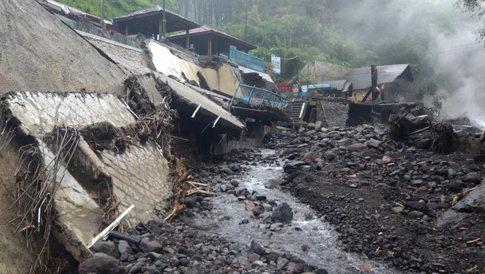 Warga berada samping bangunan yang rusak diterjang banjir bandang di Obyek Wisata Guci, Kabupaten Tegal, Jawa Tengah, Minggu (25/1/2026). Intensitas hujan yang tinggi dan rusaknya hutan di kaki Gunung Slamet mengakibatkan tiga jembatan hanyut, lima objek wisata dan sungai rusak akibat diterjang banjir bandang pada Sabtu (24/1/2026). ANTARA FOTO/Oky Lukmansyah/YU