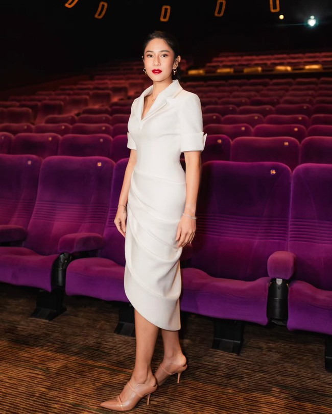 Bibir merah menyala kontras dengan gaun putih yang dikenakannya. Untuk acara istimewa tersebut, ibu dua anak ini mengenakan gaun berpotongan struktural karya desainer Hian Tjen. Unsur feminin hadir lewat detail lipit dan draperi di bagian rok. Foto: Instagram/@therealdisastr @armanfebryan