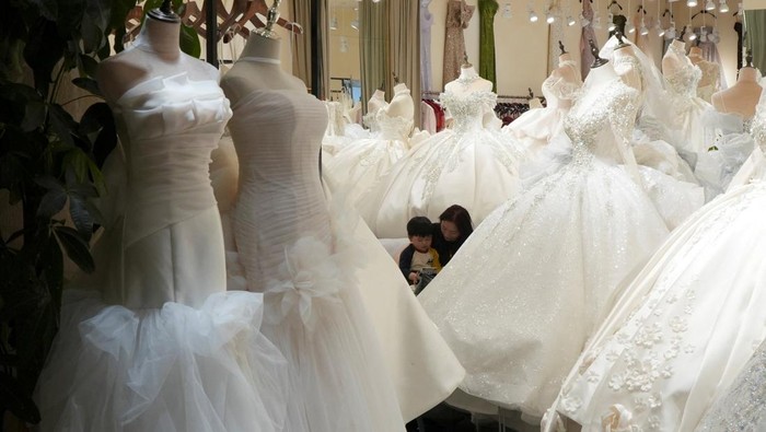A shopkeeper reads with a child at Huqiu Bridal City in Suzhou, Jiangsu province, China January 16, 2026. REUTERS/Nicoco Chan