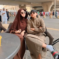 Saat bersantai bersama suami di sela-sela ibadah di Tanag Suci, ia memilih hijab model bergo berwarna cokelat tua yang senada dengan gamisnya. Tampilan earth tone ini dipermanis dengan penggunaan kacamata hitam, memberikan kesan modern namun tetap syari. Foto: Dok. Instagram @bellabonita_r.a.