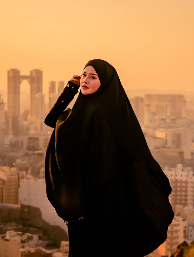 Bella Bonita Rafnortfic Agassy mengunggah momen saat menjalani umrah bersama suami, Denny Caknan dan anaknya. Bella Bonita tampil menawan dalam balutan khimar dan abaya berwarna hitam. Foto: Dok. Instagram @bellabonita_r.a.