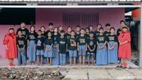 Tampak Sri Irianingsih dan Sri Rossyati berpose bersama murid-muridnya dengan latar bangunan Sekolah Darurat Kartini yang sederhana namun penuh makna perjuangan pendidikan.