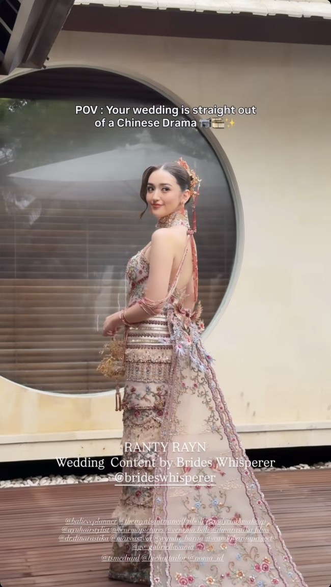 Ranty tampil anggun dalam gaun bernuansa cheongsam modern berpotongan fit body dengan kerah tinggi khas Tiongkok. Gaun berwarna dasar nude itu dipenuhi bordir floral warna pastel dan merah marun, serta dipermanis detail payet dan manik-manik yang memberi efek mewah. Potongan punggung terbuka dan tambahan kain panjang menyerupai train memberikan kesan dramatis pada penampilannya. Diketahui gaun tersebut merupakan rancangan GV by Gabriella Praditha. Foto: Instagram