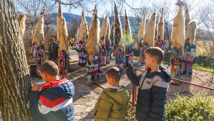 Children look at a men dressed as Didi s Kamesnice during a carnival in Gljev, Croatia, January 17, 2026. REUTERS/Antonio Bronic
