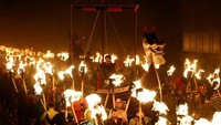 Ratusan peserta berpawai dengan obor menyala mengawal kapal panjang buatan melalui jalan-jalan Lerwick saat malam Up Helly Aa, rangkaian pawai obor yang merupakan inti dari perayaan yang berakar dari tradisi abad ke-19. REUTERS/Toby Shepheard