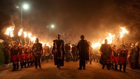 Peserta berpakaian khas Viking berjalan dengan obor menyala di Up Helly Aa, festival yang dirayakan komunitas setempat untuk menghormati warisan budaya laut dan Norse di Shetland. REUTERS/Toby Shepheard