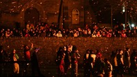 Penonton menyaksikan peserta melemparkan obor menyala selama pawai Up Helly Aa di Lerwick, festival api tahunan yang menarik pengunjung lokal dan internasional serta merayakan hubungan Shetland dengan tradisi Viking. REUTERS/Toby Shepheard