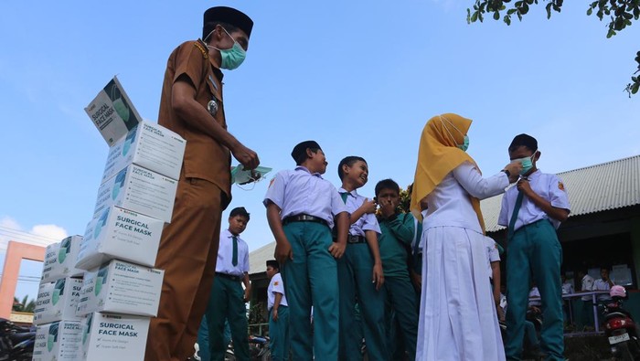 Petugas medis dari Pukesmas Samatiga membantu memakaikan masker kepada pelajar di Madrasah Tsanawiyah Negeri (MTsN) Blang Bale, Kecamatan Samatiga, Aceh Barat, Aceh, Selasa (27/1/2026). Sebanyak 600 masker dibagikan kepada siswa-siswi untuk mengantisipasi penyakit Infeksi Saluran Pernafasan Akut (ISPA) seiring semakin tebalnya kabut asap dampak Kebakaran Hutan dan Lahan (Karhutla) yang terus meluas di Kabupaten setempat. ANTARA FOTO/Syifa Yulinnas/wsj.