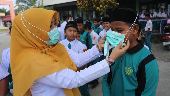 Petugas medis dari Pukesmas Samatiga membantu memakaikan masker kepada pelajar di Madrasah Tsanawiyah Negeri (MTsN) Blang Bale, Kecamatan Samatiga, Aceh Barat, Aceh, Selasa (27/1/2026). Sebanyak 600 masker dibagikan kepada siswa-siswi untuk mengantisipasi penyakit Infeksi Saluran Pernafasan Akut (ISPA) seiring semakin tebalnya kabut asap dampak Kebakaran Hutan dan Lahan (Karhutla) yang terus meluas di Kabupaten setempat. ANTARA FOTO/Syifa Yulinnas/wsj.