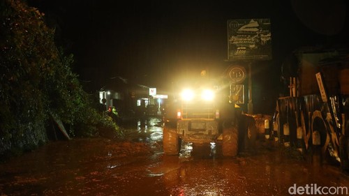 Satu alat berat sedang wara-wiri membersihkan onggokan tanah sisa longsor di Jalan Raya Ceking, Gianyar, dari tebing, Rabu (28/1/2026). (Aryo Mahendro/detikBali).