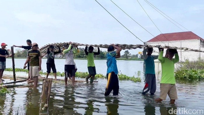 Warga terdampak luapan sungai Bengawan Jero Lamongan membuat jembatan bambu