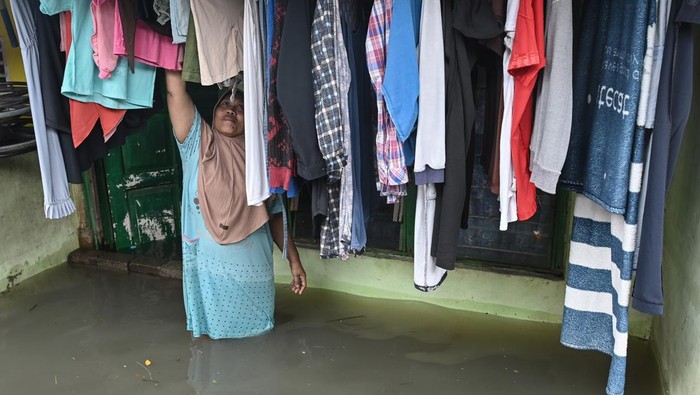 Warga menjemur pakaian di depan rumahnya yang terendam banjir di Kelurahan Kedaung Kali Angke, Cengkareng Jakarta, Kamis (29/1/2026). BPBD DKI Jakarta melaporkan terdapat 20 rukun tetangga (RT) yang terendam banjir dengan ketinggian setengah meter hingga 1,5 meter. ANTARA FOTO/Sulthony Hasanuddin/rwa.