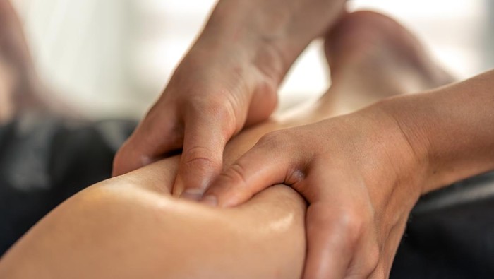 Close view of thumb work on calf trigger areas with oil. Controlled pressure supports myofascial release and restores lightness.