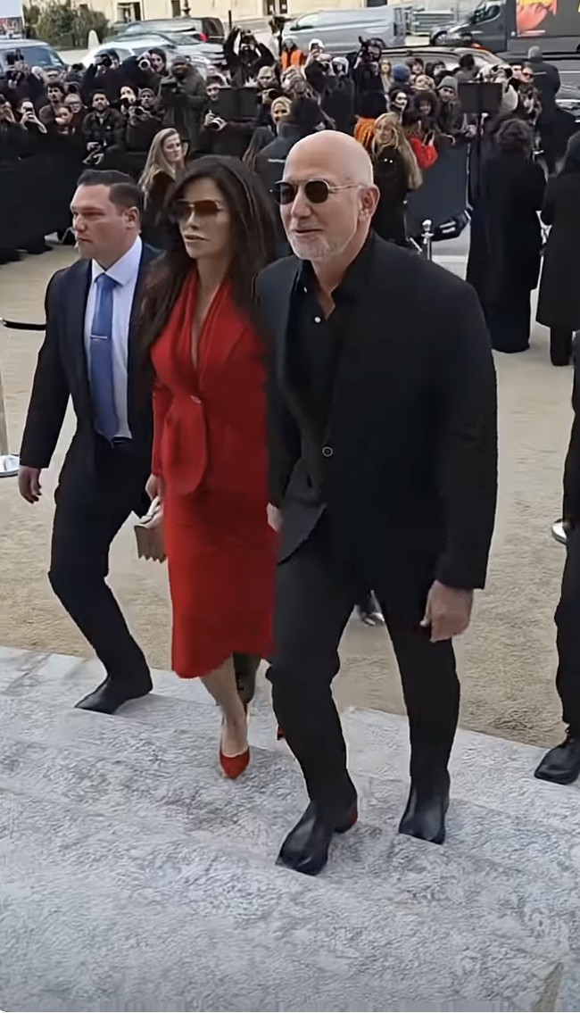 Di peragaan Schiaparelli, Senin (26/1/2026), Lauren Sanchez bersolek dengan tampilan serba merah mencolok. Ia memakai blus bergaya blazer berbelahan dada rendah yang mengikuti lekuk tubuhnya. (Foto: YouTube)