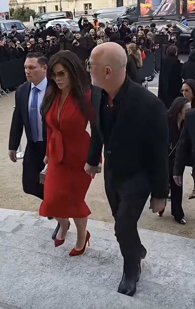 Atasan tersebut dipadukan dengan rok dan heels senada. Ia lalu menyempurnakan gayanya dengan handbag Schiaparelli yang dihiasi ornamen Surealis yang khas. Sementara itu, suaminya yang juga bos Amazon memilih setelan hitam dengan kemeja yang kancing kerahnya dibiarkan terbuka. (Foto: YouTube)