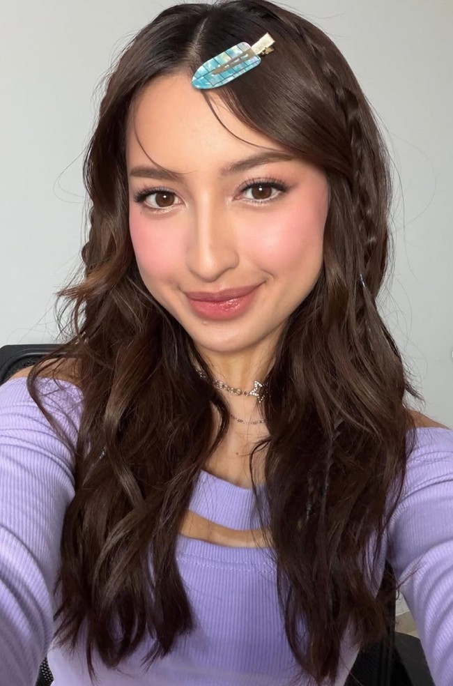 Complexionnya tampak flawless, dewy, dan halus. Blush on pink diaplikasikan cukup bold di pipi, memberi efek ‘blushing look’. Alis dibentuk natural, rapi tanpa terlalu tebal. Eye makeup soft dengan sentuhan shimmer halus, bulu mata lentik namun tetap ringan. Sementara bagian bibir menggunakan lipstik pink glossy yang membuat tampilan lebih segar. Foto: Instagram/@jennifercoppenreal20