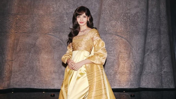 Lisa BLACKPINK dilantik sebagai duta pariwisata Thailand. Tampil memakai gaun emas, terinspirasi desain Balmain untuk Ratu Thailand Sirikit Kitiyakara.
