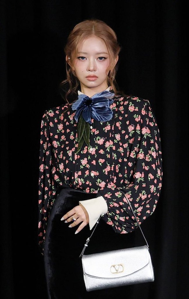 Personel IVE asal Jepang, Rei tampak kawaii dengan model rambut bun. Dibalut atasan hitam bermotif floral, pilihan rok hitam berbahan beludru, high heels, dan hand bag berwarna silver. Foto: Instagram