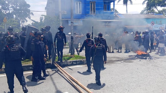 Personel Brimob saat hendak membubarkan massa yang memblokade jalan di Mimika imbas penikaman maut.