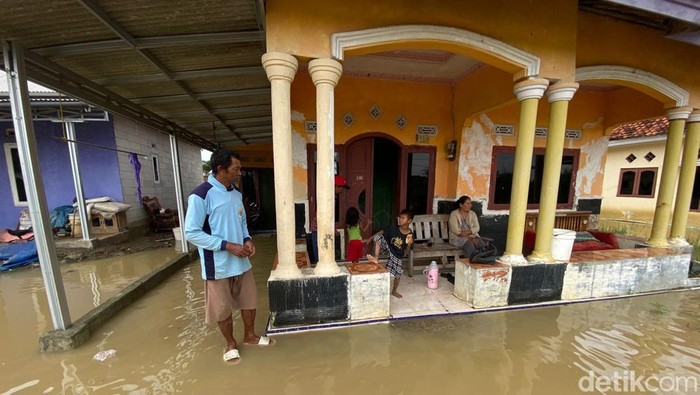 Tampak seorang warga berada di teras rumahnya yang tergenang air akibat luapan Sungai Cipanas, Desa Santing, Kecamatan Losarang, Kabupaten Indramayu, Jumat (30/1/2026) siang.