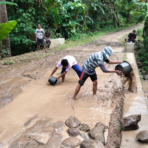 Warga Desa Lamatutu, Kecamatan Tanjung Bunga, Kabupaten Flores Timur, NTT, mencedok lumpur serta menimbun batu di jalan kabupaten tersebut, Jumat (30/1/2026). (Warga/Pirrlo Luron)