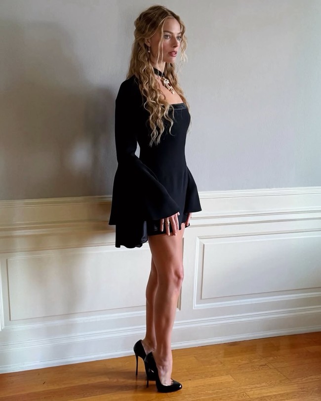 Robbie memulai rangkaian tur Wuthering Heights pada 26 Januari dengan mengenakan minidress hitam Roberto Cavalli Resort 2026 yang menampilkan lengan lonceng dramatis serta garis leher persegi beraksen beludru. Ia melengkapinya dengan kalung liontin rubi dan emas mencolok pada choker beludru hitam, serta sepatu stiletto kulit paten Christian Louboutin dengan hak setinggi 12 cm. (Foto: Instagram/@andrewmukamal)