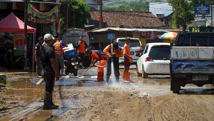 Personel BPBD Tulungagung menyemprotkan air saat membersihkan endapan lumpur dari atas aspal Jalan Raya Popoh, Tulungagung, Jawa Timur, Sabtu (31/1/2026). Pembersihan pascabanjir akibat hujan berintensitas tinggi tersebut dilakukan agar aktivitas masyarakat kembali normal dan akses jalan penghubung menuju jalur lintas selatan Tulungagung dapat dilalui kendaraan dengan aman. ANTARA FOTO/Destyan Sujarwoko/wsj.