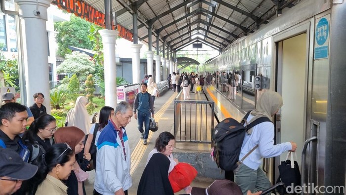 Penumpang mengantri memasuki kereta di stasiun kereta