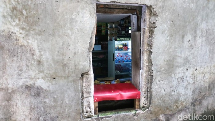 Dua pekerja membeli makanan dan minuman melalui lubang kecil di tembok pembatas kawasan permukiman dan pusat perbelanjaan di Kemang, Jakarta, Selasa (31/1/2026).