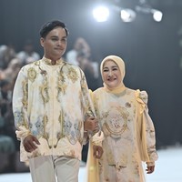 Ibu Ratih tampil bersahaja mengenakan gaun panjang berwarna cream dipadu dengan cape kuning pastel dengan motif floral yang memberikan kesan lembut dan feminin. Penampilan keduanya sontak curi atensi publik. Foto: Dok. Garis Poetih.