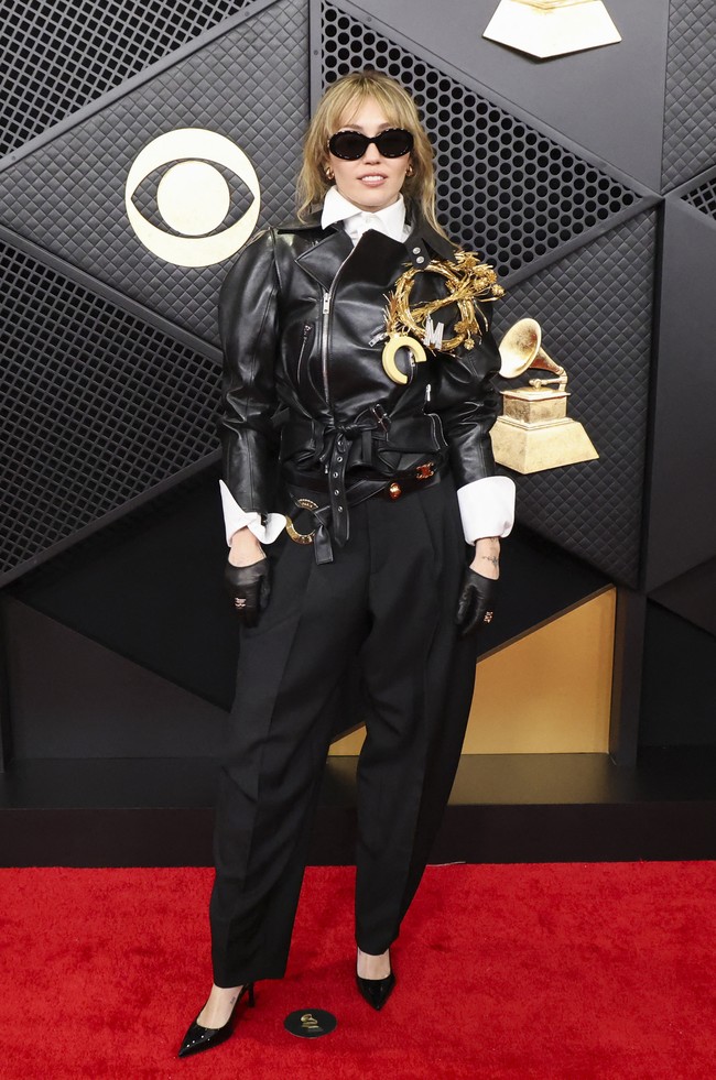 Miley Cyrus kembali mencuri perhatian di karpet merah Grammy Awards 2026 dengan penampilan yang berani dan tak terduga. Alih-alih mengenakan gaun seperti kebanyakan selebritas, penyanyi berusia 33 tahun itu tampil dengan busana rancangan Celine. Ia memadukan jaket kulit hitam yang dikenakan ritsleting penuh di atas kemeja putih rapi, serta dihiasi bros berukuran besar yang menjadi pusat perhatian. (Foto: REUTERS/Mario Anzuoni)
