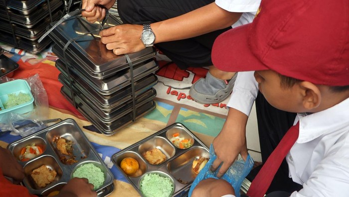 Guru membagikan Makanan Bergizi Gratis (MBG) pada siswa saat sekolah diliburkan akibat bangunan ambruk di Madrasah Ibtidaiyah Miftahul Falah, Gunungputri, Kabupaten Bogor, Jawa Barat, Senin (2/2/2026).  Pemerintah memastikan program Makan Bergizi Gratis (MBG) tetap berjalan selama Ramadhan dengan menu dan waktu pemberian MBG disesuaikan bagi penerima manfaat yang menjalankan ibadah puasa. ANTARA FOTO/Yulius Satria Wijaya