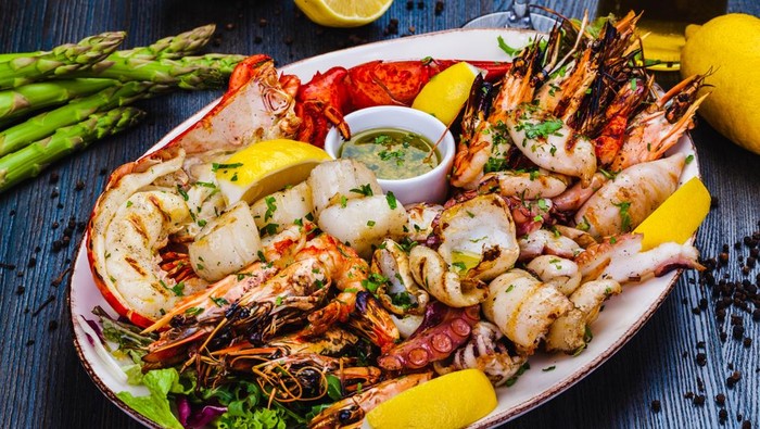 Seafood platter. Grilled lobster, shrimps, scallops, langoustines, octopus, squid on white plate.
