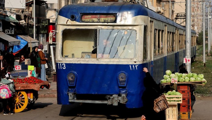 People stand near a tram in the Mediterranean city of Alexandria, Egypt, January 25, 2026. The Alexandria tram dates to 1860, and it started moving in 1863. REUTERS/Mohamed Abd El Ghany
